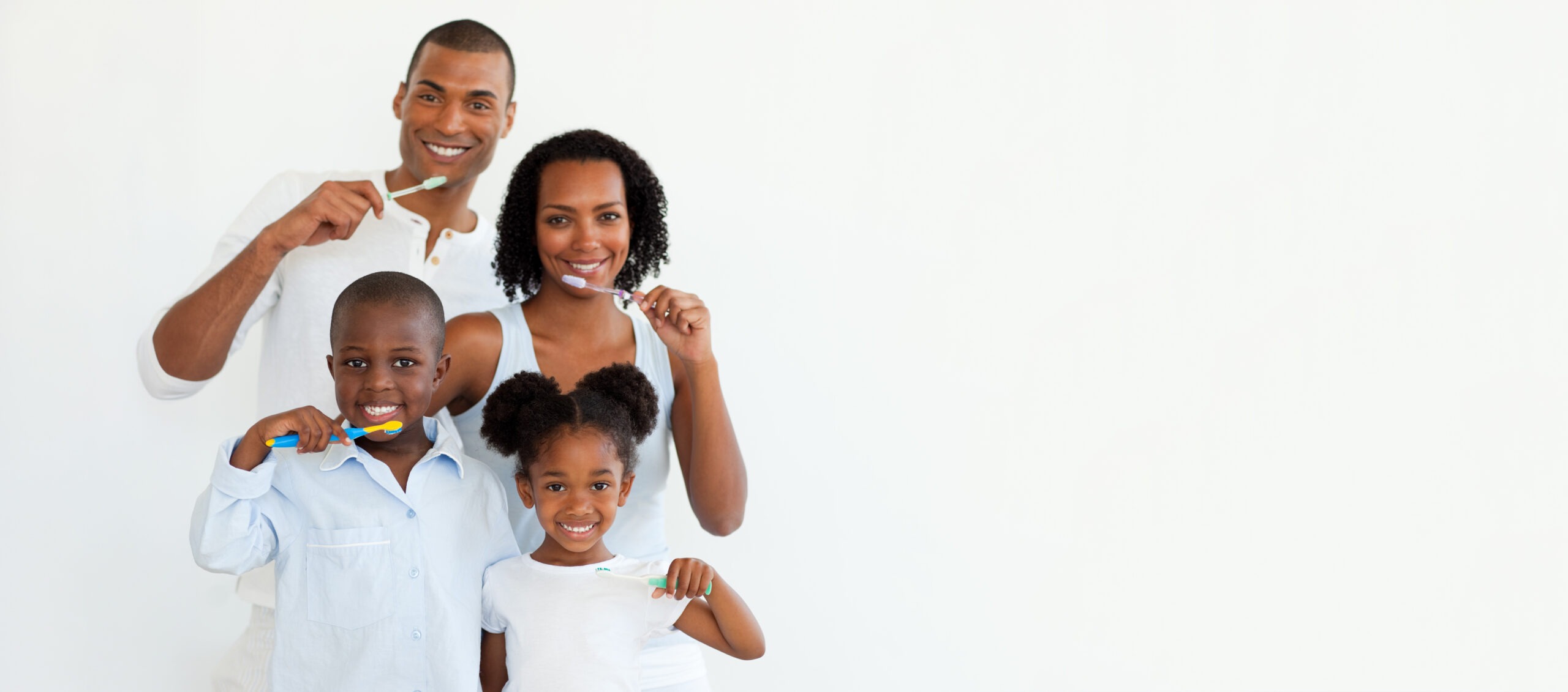 A family of four smiles while brushing their teeth, promoting dental hygiene in a bright, simple setting.