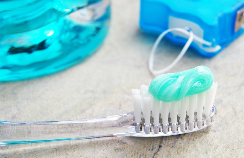 Toothbrush with mint toothpaste beside mouthwash and dental floss, highlighting essential dental hygiene products for oral care.